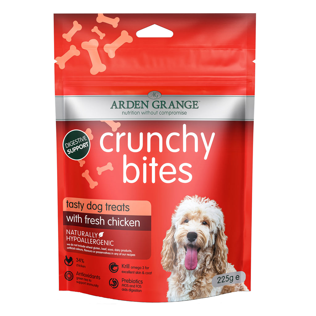 A red stand-up pouch of Arden Grange Crunchy Bites dog treats with a photo of a fluffy light-colored dog on the front. The package highlights 'tasty dog treats with fresh chicken' and shows product details like 'Naturally Hypoallergenic' and 'Digestive Support'.